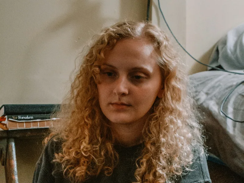 A young woman sitting quietly in a bedroom
